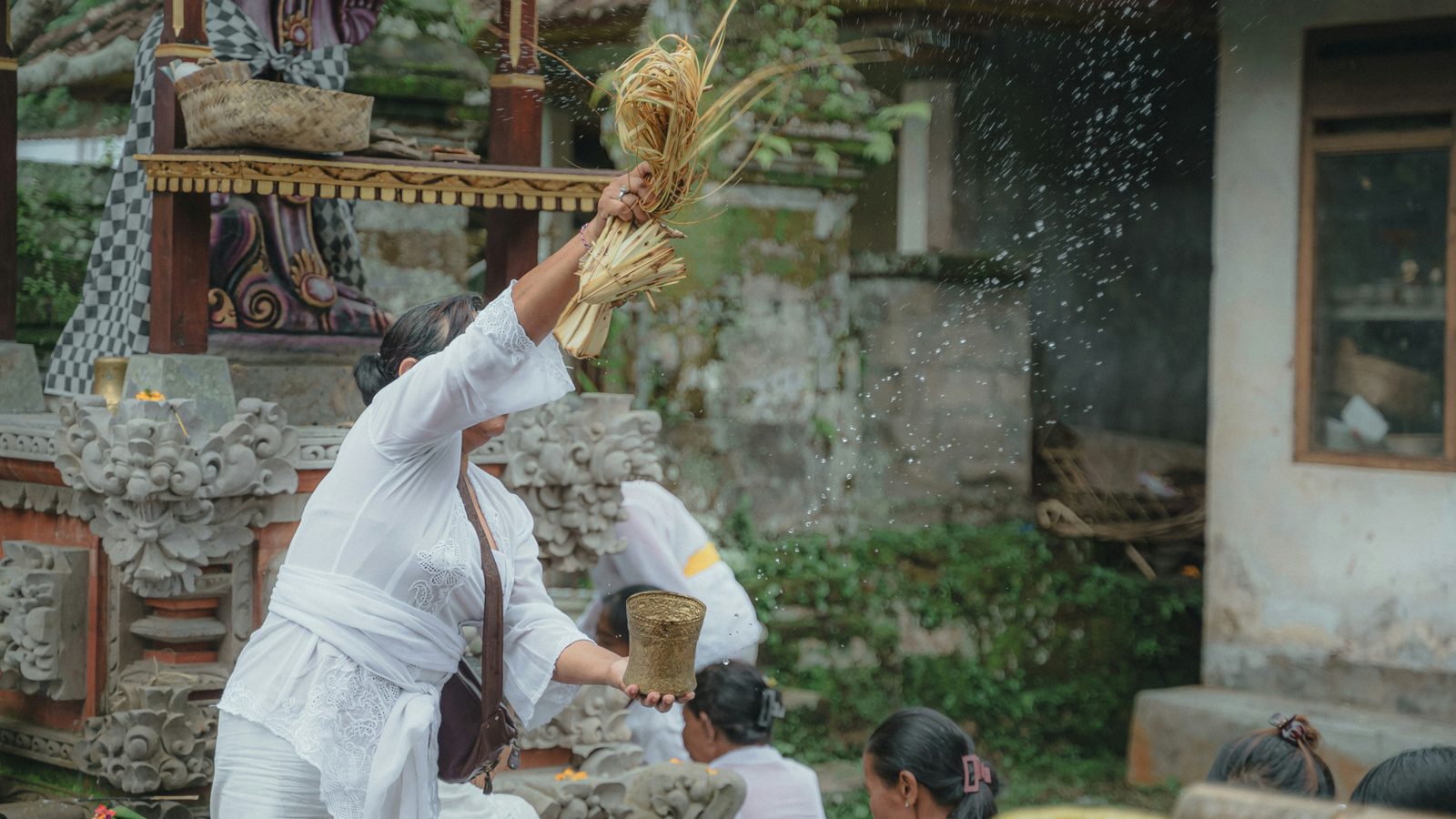 Balinese Holy Priest is Splashing a Holy Water to the people before and after pray, in procession of Ngaben Ceremony in Bali. Photo credit: Krisna Yuda on Unsplash.